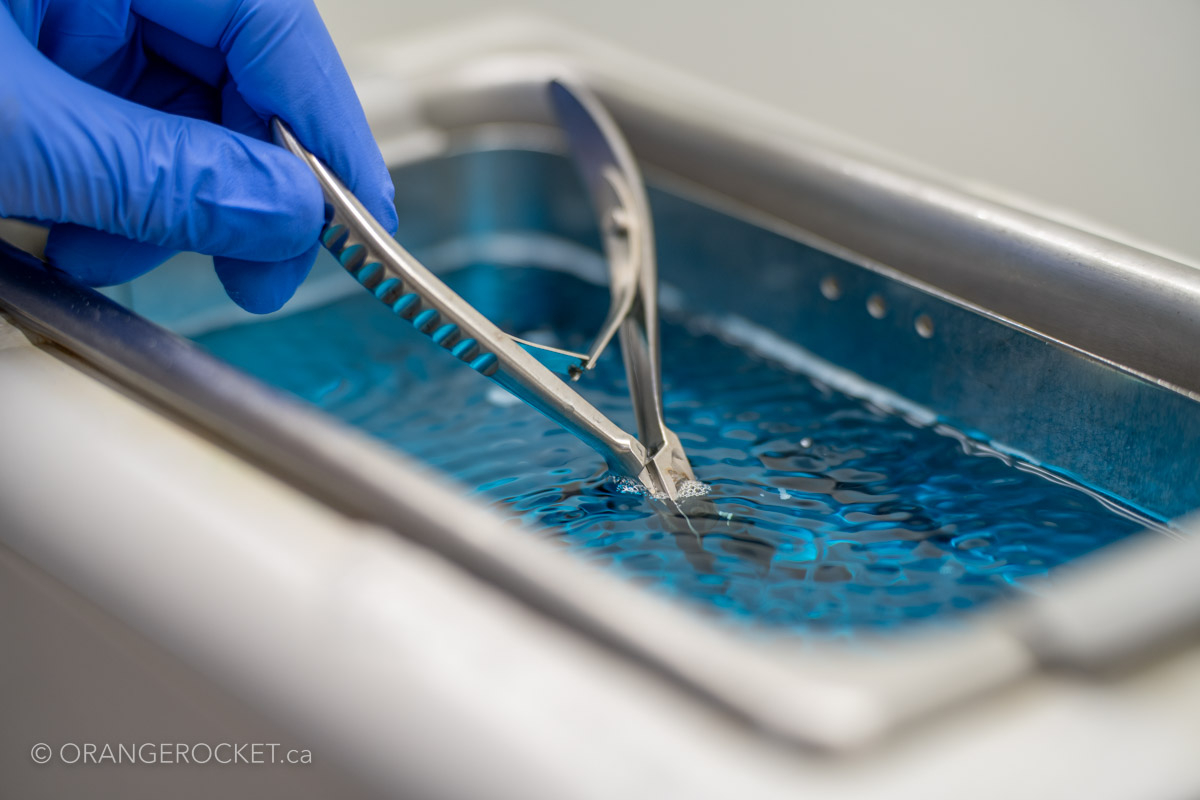 Gloved hands cleaning clinical instruments